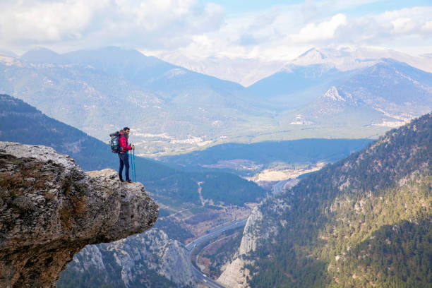 istock Young man with backpack standing on edge cliff on top of mountain. 1173426395