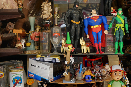 Athens, Greece - August 7, 2019: Superhero action figures miniature toy cars and other vintage objects on display at antiques store.