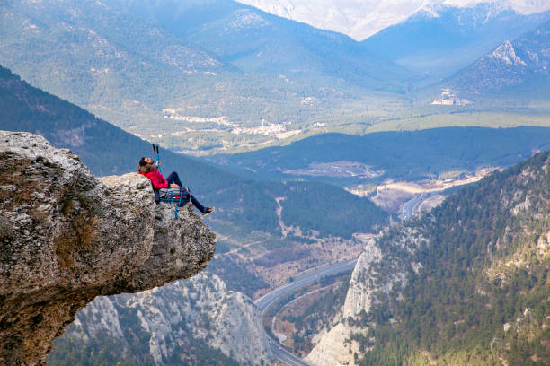 istock Young man with backpack standing on edge cliff on top of mountain. 1173427526