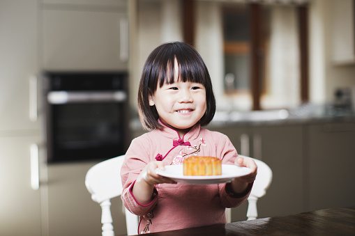 toddler girl eating moon cake and celebrating Mid Autumn festival