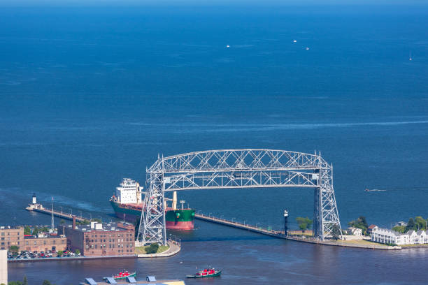 Ship Entering Harbor On Lake Superior A ship passing under a lift bridge into harbor. cantilever bridge stock pictures, royalty-free photos & images