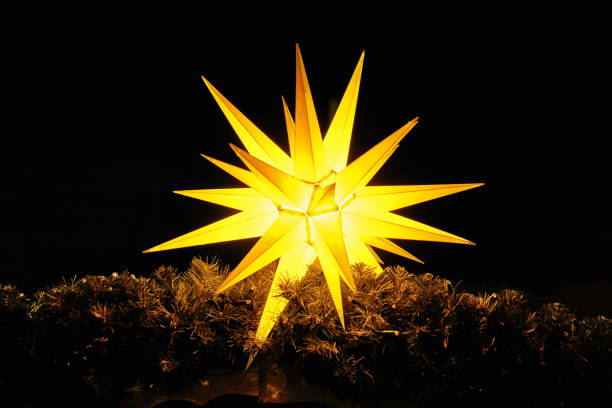 Luminous christmas star on fir branches. Christmas decoration in the night. Luminous christmas star on fir branches. Christmas decoration in the night. licht stock pictures, royalty-free photos & images