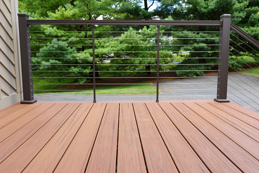 Closeup of new composite wood deck with modern wire railing.