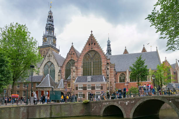 View of the Oude Kerk Calvinist church. The Oude Kerk is Amsterdam’s oldest building (XIV c.). It stands in De Wallen, now Amsterdam's main red-light district. Amsterdam, Netherlands - June 25, 2017: View of the Oude Kerk Calvinist church. The Oude Kerk is Amsterdam’s oldest building (XIV c.). It stands in De Wallen, now Amsterdam's main red-light district. wellen stock pictures, royalty-free photos & images