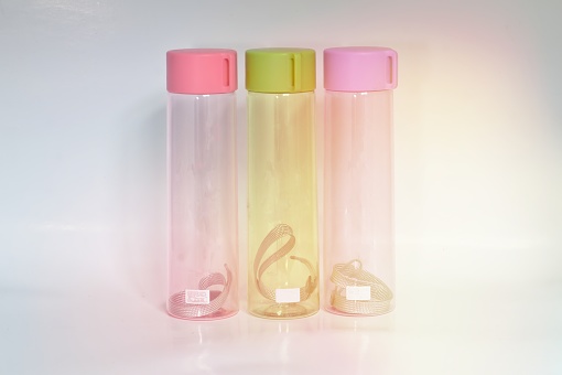 Conical clear plastic water bottle Three leaves, green lid, pink, purple, bright morning light White background