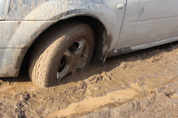 car wheel stuck in mud slips in a puddle on the road