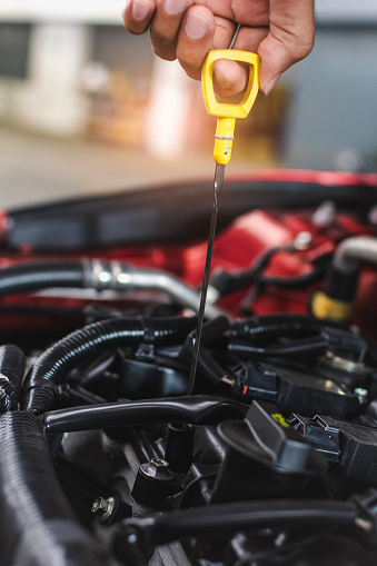 Man servicio mecánico mantenimiento de mantenimiento de mantenimiento coche de mantenimiento coche Compruebe el coche de nivel de aceite del motor en la sala de exposición del garaje concesionario borroso.