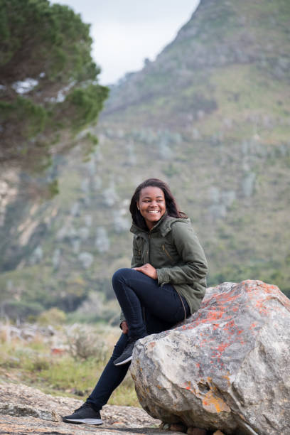 Smiling woman looking away while sitting on rock
