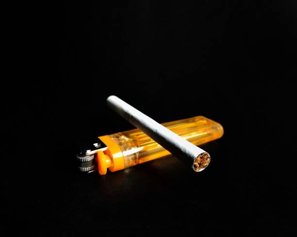 istock Yellow lighter with cigarette on black background. vices 1173482848