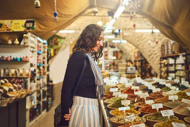 Shot of a young woman shopping for spices at a local market stall
