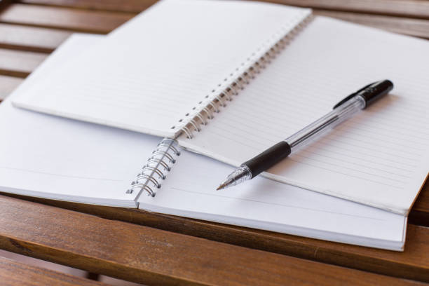 istock Selective focus of Pen, notebook on the wooden table with warm light and copy space 1173484211