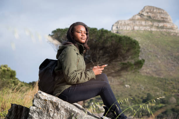 istock Female hiker looking away while sitting on rock 1173484284