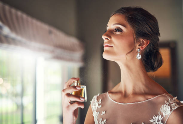 Classic scent for a classic bride Shot of a beautiful young bride spraying perfume on her neck in preparation for her wedding day bridal shop photos stock pictures, royalty-free photos & images