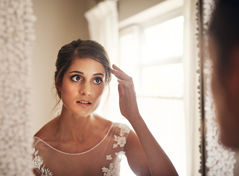 Shot of a beautiful young bride looking at herself in the mirror on her wedding day