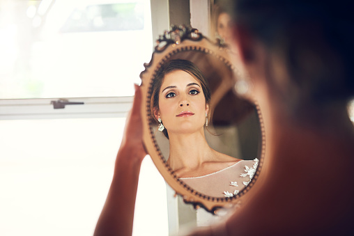 Shot of a beautiful young bride looking at herself in the mirror on her wedding day