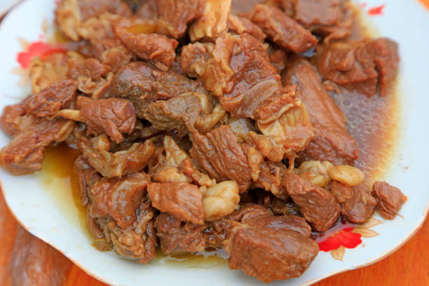 Meat in red sauce with mushrooms on a plate. Festive meal.
