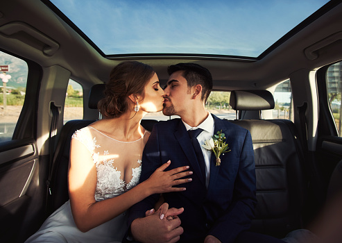 Shot of a happy young couple kissing in a car on their wedding day