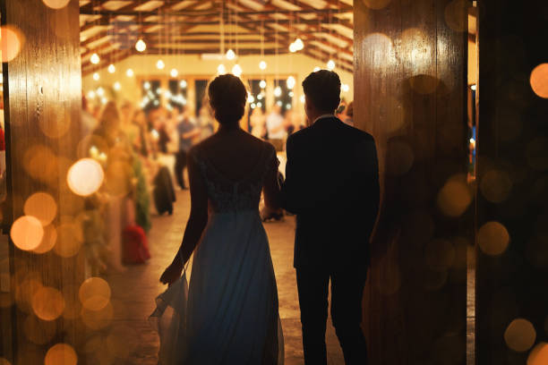 Making a grand entrance into marriage Rearview shot of a young couple arriving hand in hand at their wedding reception wedding reception photos stock pictures, royalty-free photos & images