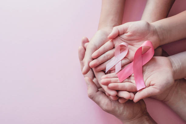 hands holding pink ribbons on pink background, Breast cancer awareness and October Pink day stock photo