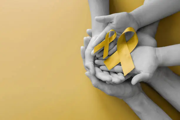 adult and children hands holding yellow gold ribbon, Sarcoma Awareness, Bone cancer, childhood cancer awareness