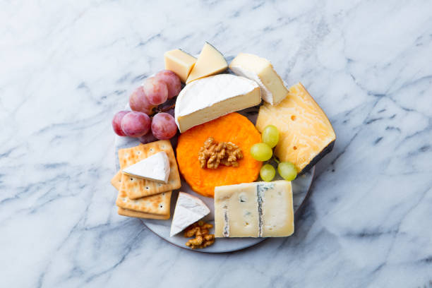 assortiment de fromage, raisins et craquelins. fond de marbre. vue du haut. copiez l'espace. - cheese portion cracker cheddar photos et images de collection