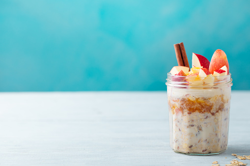 Overnight oats, bircher muesli with apple, cinnamon and honey. Blue background. Copy space