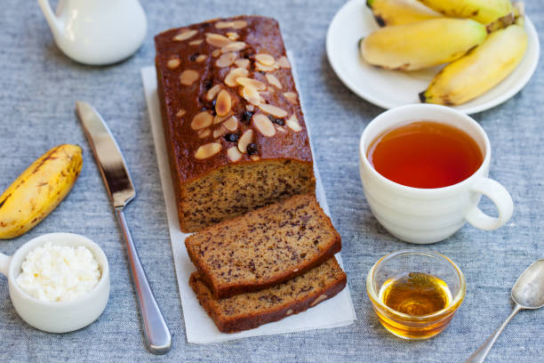 ciasto bananowe, bochenek z czekoladą i filiżanka herbaty na szarym tle tekstylnym. - pie coconut dessert plate zdjęcia i obrazy z banku zdjęć