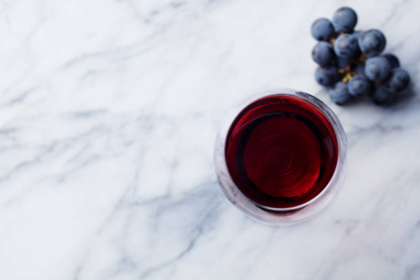 大理石のテーブルの背景に新鮮なブドウとガラスの赤ワイン。トップビュー。スペースをコピーします。 - directly above wineglass glass wine ストックフォトと画像