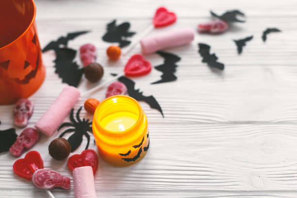istock Halloween candy , jack o lantern bucket, candle and skulls, black bats, ghost, spider decorations on white wooden background. Copy space. Trick or treat 1173505259