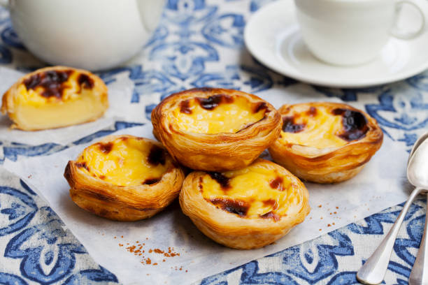 tarta jajeczna, tradycyjny portugalski deser, pastel de nata na pergaminowym papierze. niebieskie tło. - food close up sweet bun dessert zdjęcia i obrazy z banku zdjęć