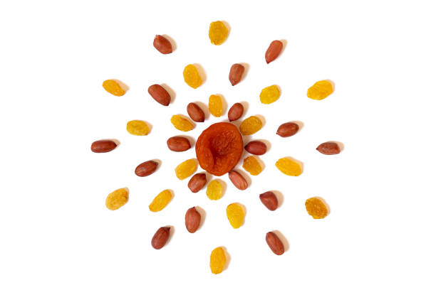 Pattern of Nuts - yellow raisins, dried apricots and peeled peanuts on a white background in the form of a circle. Concepts about decoration, healthy eating and food background.