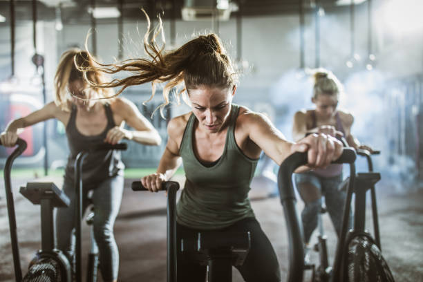 groupe de femmes athlétiques sur des vélos d'exercice dans un club de santé. - spinning instructor exercising gym photos et images de collection
