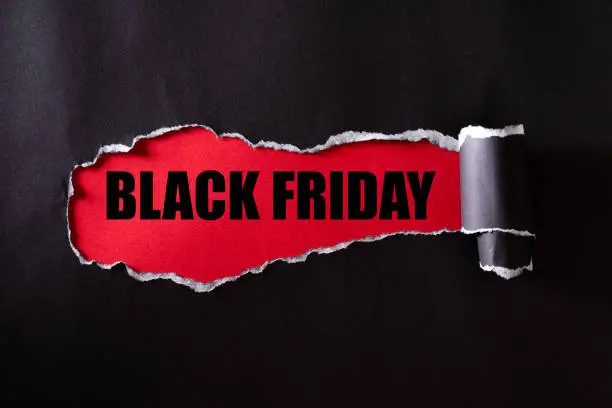 Photo of Top view of Black torn paper and the text black friday on a red background. Black Friday composition.