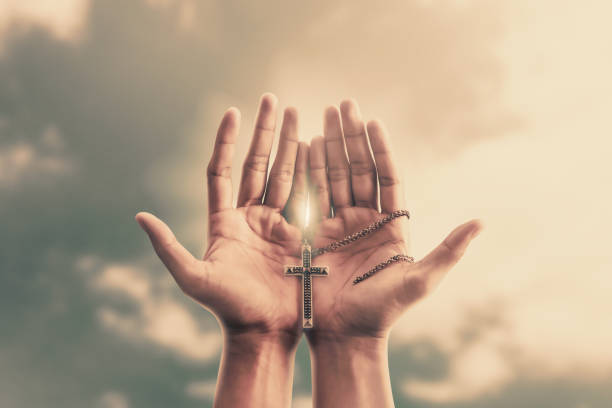 praying hands hold a crucifix or cross of metal necklace with faith in religion and belief in god on confession background. power of hope or love and devotion. - prayer beads imagens e fotografias de stock