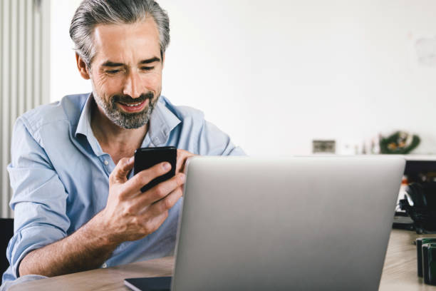 istock happy man looking at mobile in front of laptop 1173517104