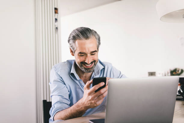 istock happy man looking at mobile in front of laptop 1173517135