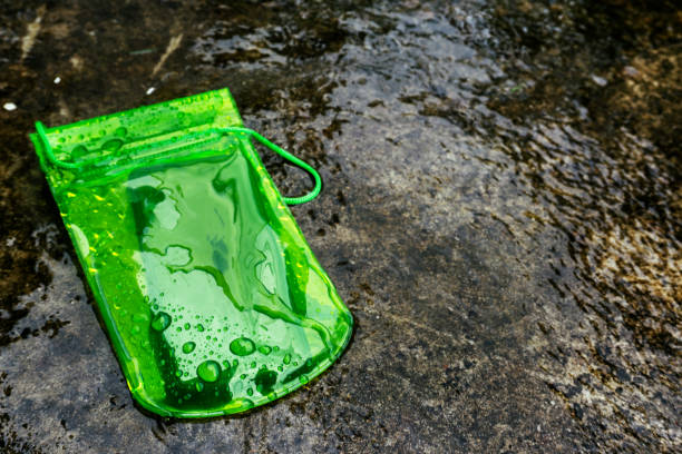 istock Green waterproof mobile phone case with water droplets on black texture background.PVC zip lock bag protect mobile phone or important items from water.Concept for Songkran water festival in Thailand. 1173517253