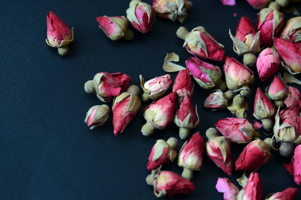 istock Dried rose buds scattered on a dark surface. Rose tea close up 1173517328