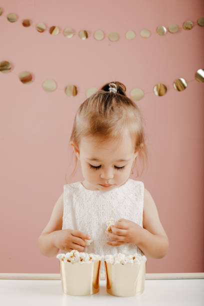 A little girl with ponytails and a crown pulled her lips out like a duck in a kiss. The child indulges and makes faces. Crazy funny girl. Portrait on a sea-green background.