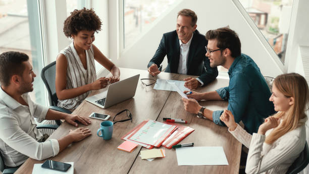 istock Sharing new ideas. Group of young business people discussing something and smiling while sitting at the office table 1173523078