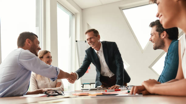istock Congratulations! Two cheerful colleagues shaking hands and smiling while sitting in the modern office 1173523079