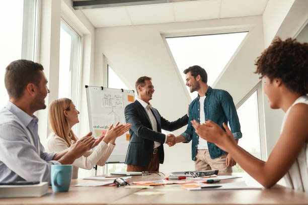 istock Welcome to our team! Two cheerful colleagues shaking hands and smiling while having a meeting in the modern office 1173523100