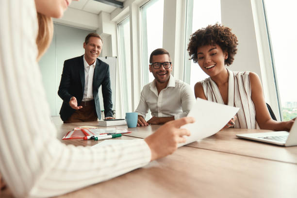 istock Great results! Group of young business people looking at documents and smiling while sitting at the office table 1173523824