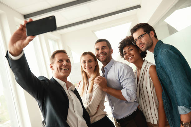 istock Happy team! Group of smiling colleagues taking selfie while standing in the modern office 1173524057