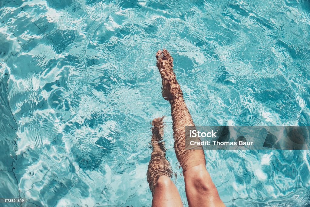 Beautiful womans legs in the pool Highangle view of beautiful legs in a splashing pool Swimming Pool Stock Photo
