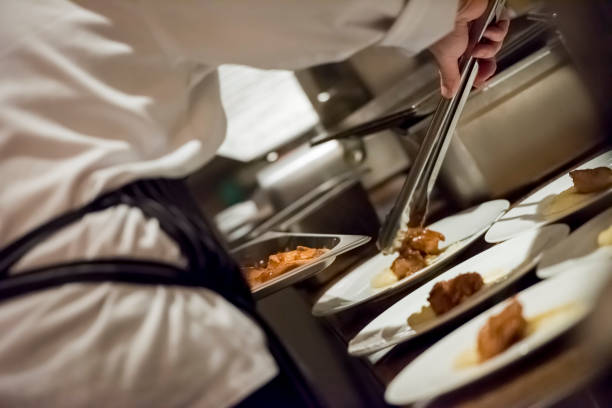 Close up photo of chef serving food on the plates at the kitchen, selective focus