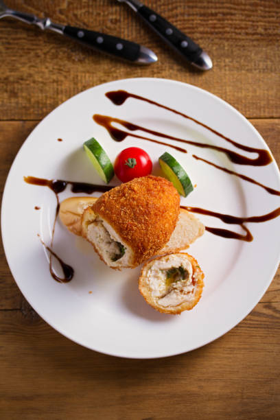 istock Chicken Kiev and vegetables on white plate, wooden background 1173524711