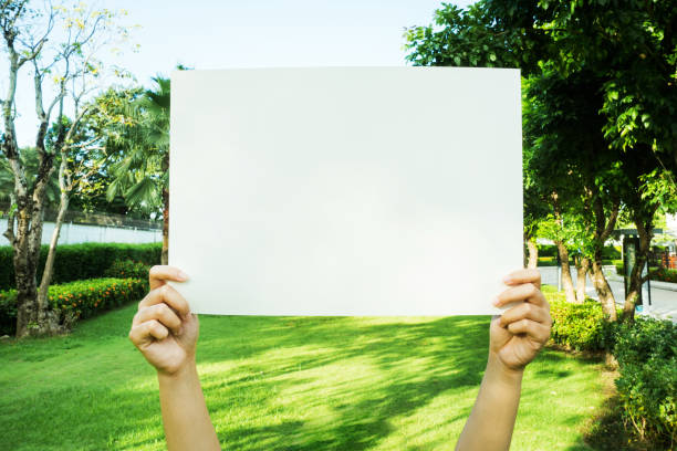 istock hand holding white blank paper in the park 1173525081