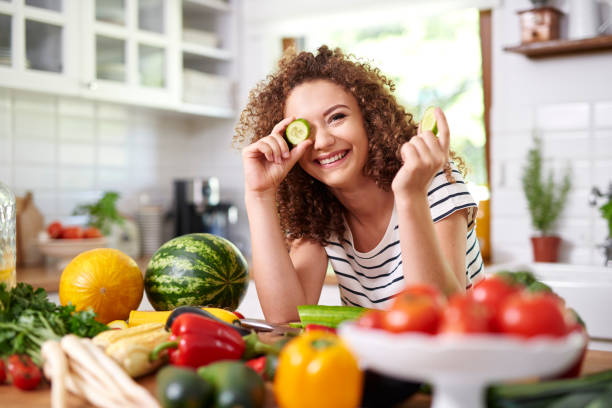 femme retenant une tranche de concombre - vegeterian photos et images de collection