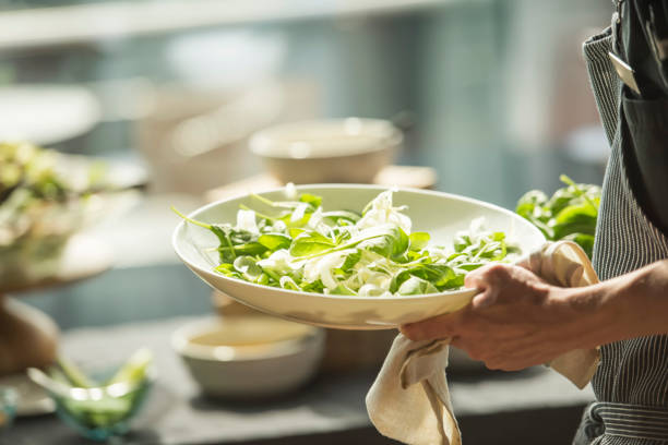 Close up photo of waiter holding plate with salad, selective focus